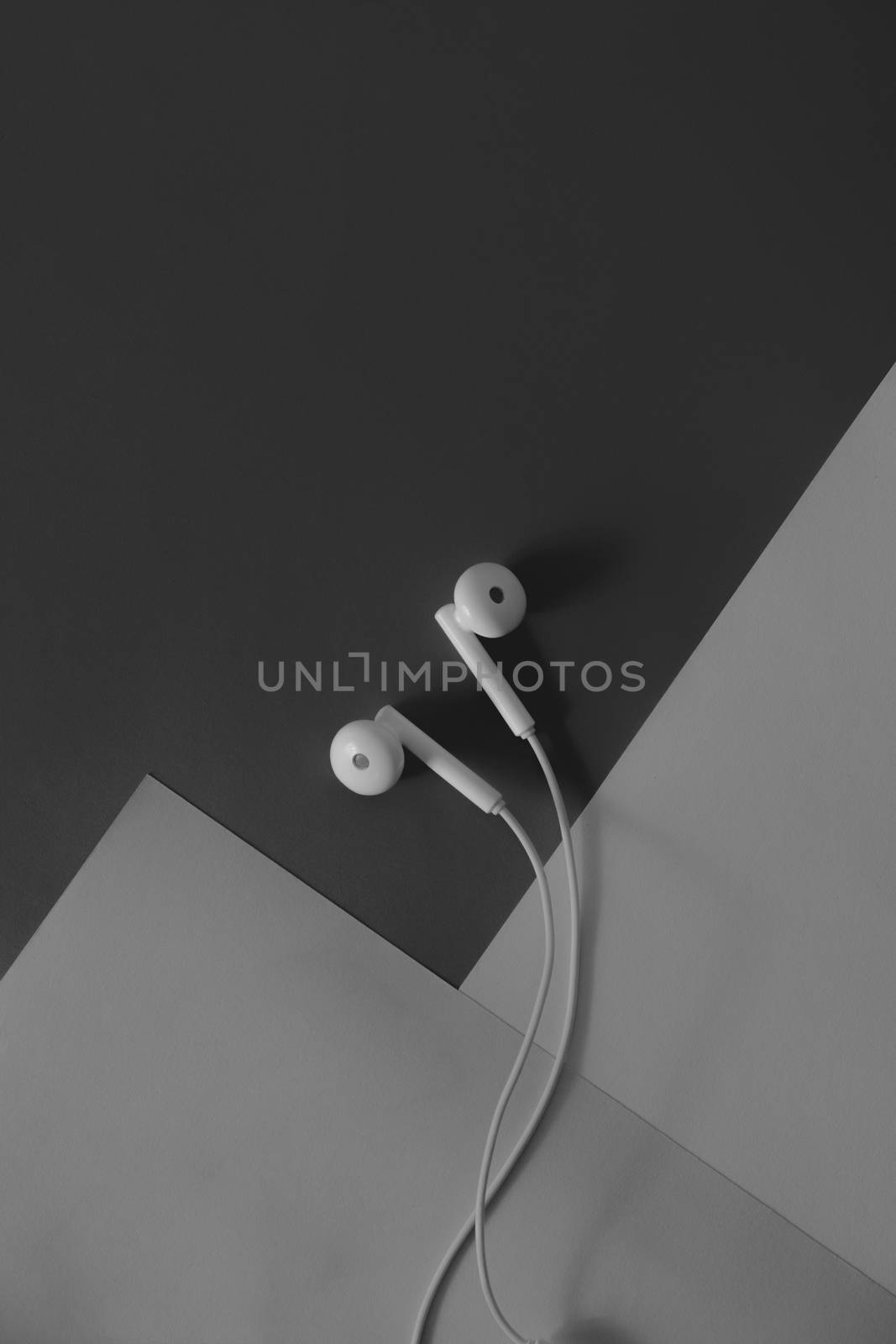pair of in-ear headphones on dark black and white background by photoboyko