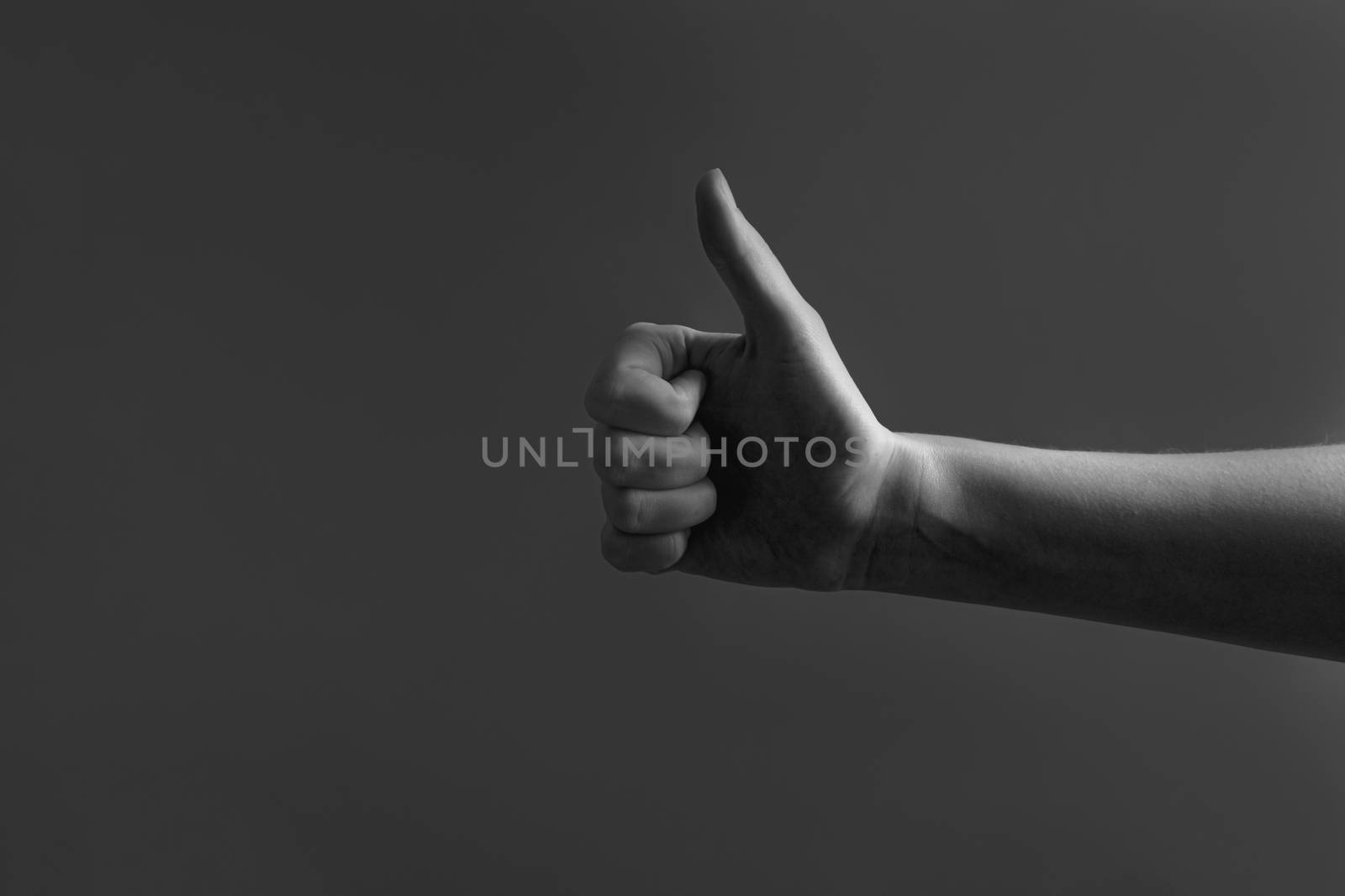 Thumbs up, approval gesture concept. Hand showing a "thumb up" sign in low key background