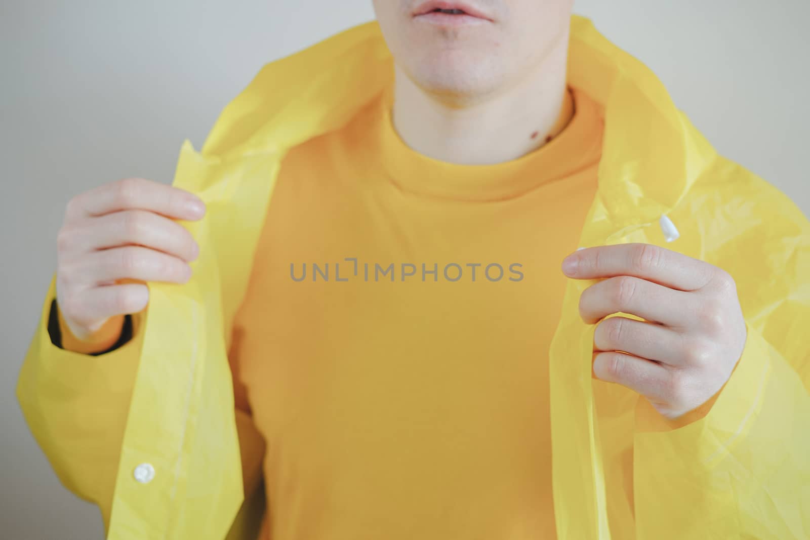 Male person in yellow t-shirt and raincoat. by photoboyko