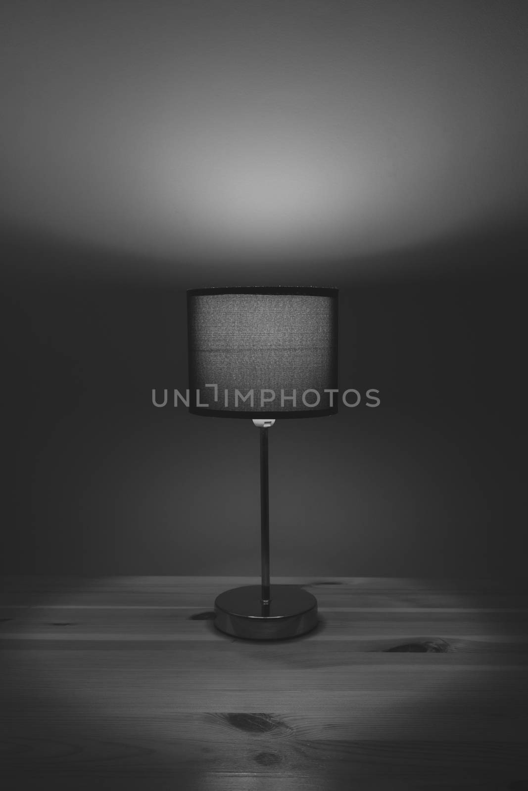 Electric lamp on the table top, monochrome low key. Cozy bedroom light at night, minimalistic and sparse image