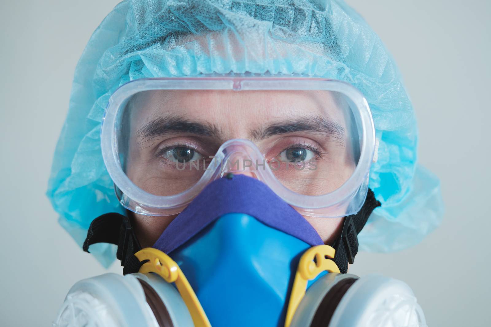 Man in protective face mask, eyeglasses and head protection, focus on eyes. Medical personell, scientist or MD in work gear, concept of covid-19, virus, epidemic and vaccine development