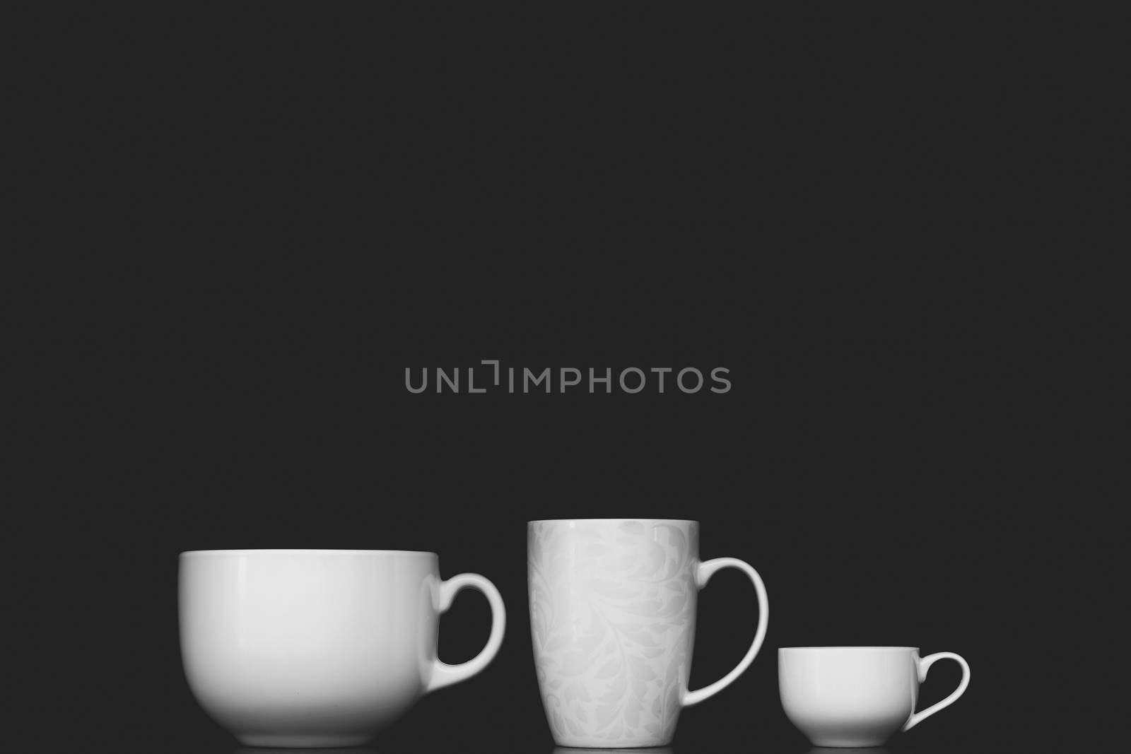 Three white cups with different shapes, low key monochrome. by photoboyko