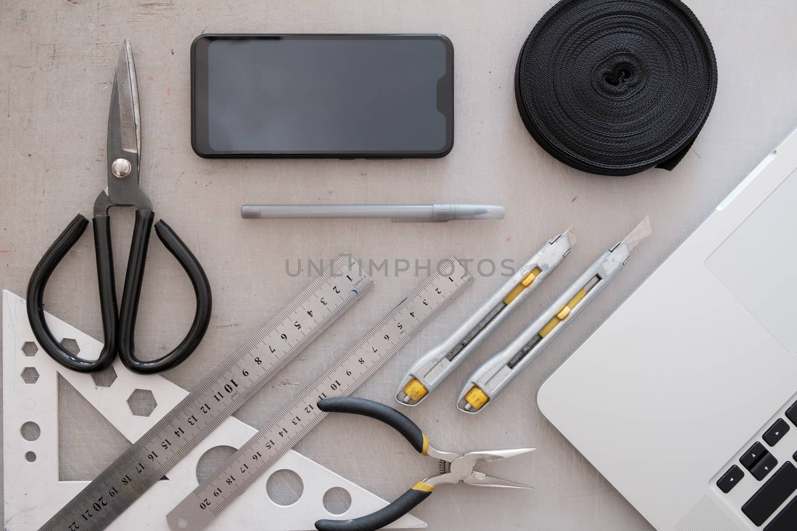 Engineering or industrial designer work place, top view. Flat lay with laptop computer, smartphone, rope, scissors, rulers and knifes with grunge backdrop
