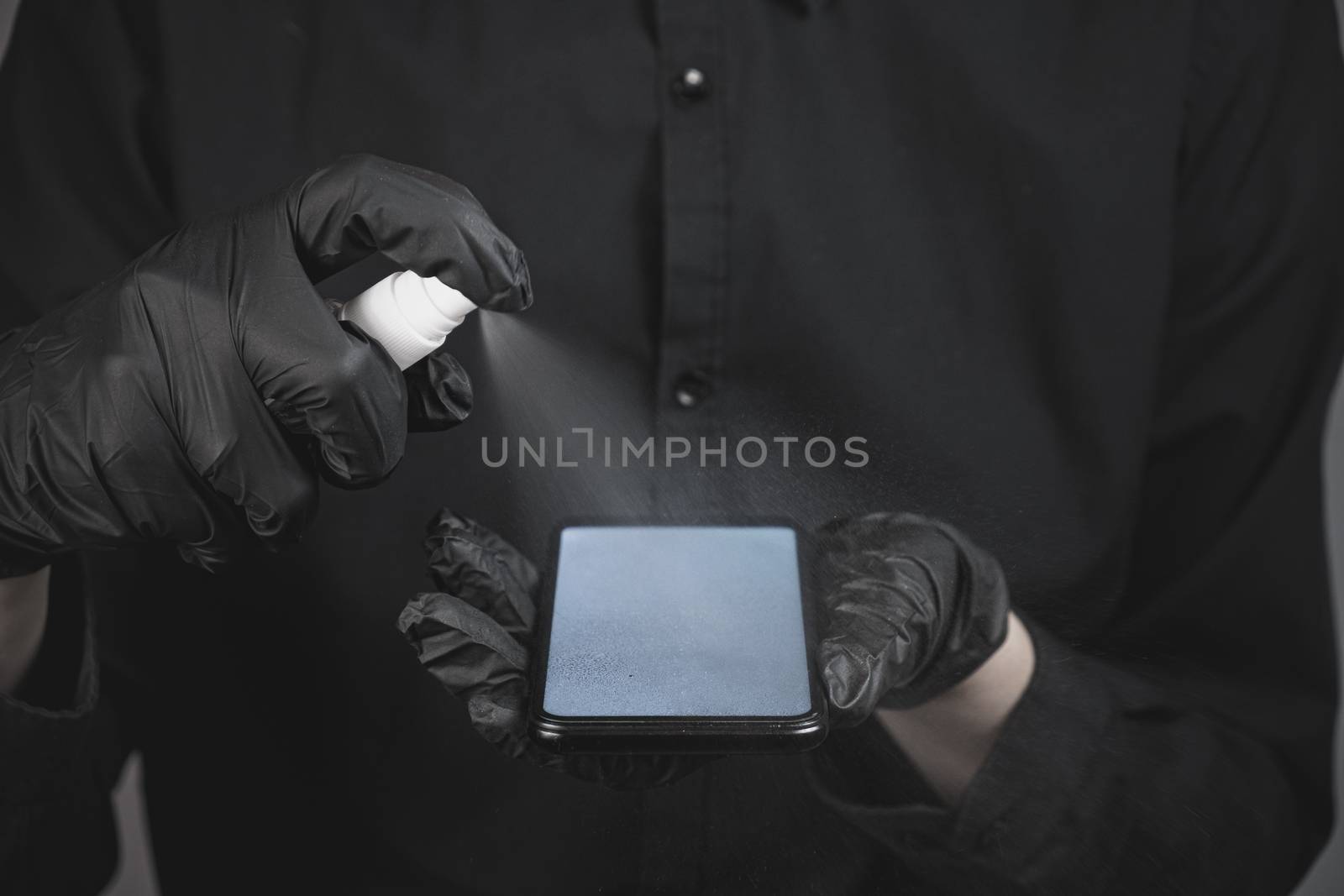 Cleaning the phone with a sanitizer, total black concept by photoboyko