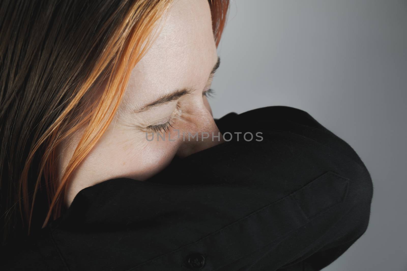 Woman sneezes into her sleeve - concept of keeping virus or infection. Woman covers nose and mouth with hands trying to sneeze, personal hygiene or health care