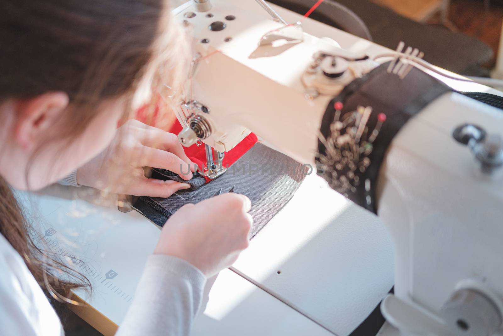 Seamstress doing precise work, shoulder view. Needlewoman at ove by photoboyko