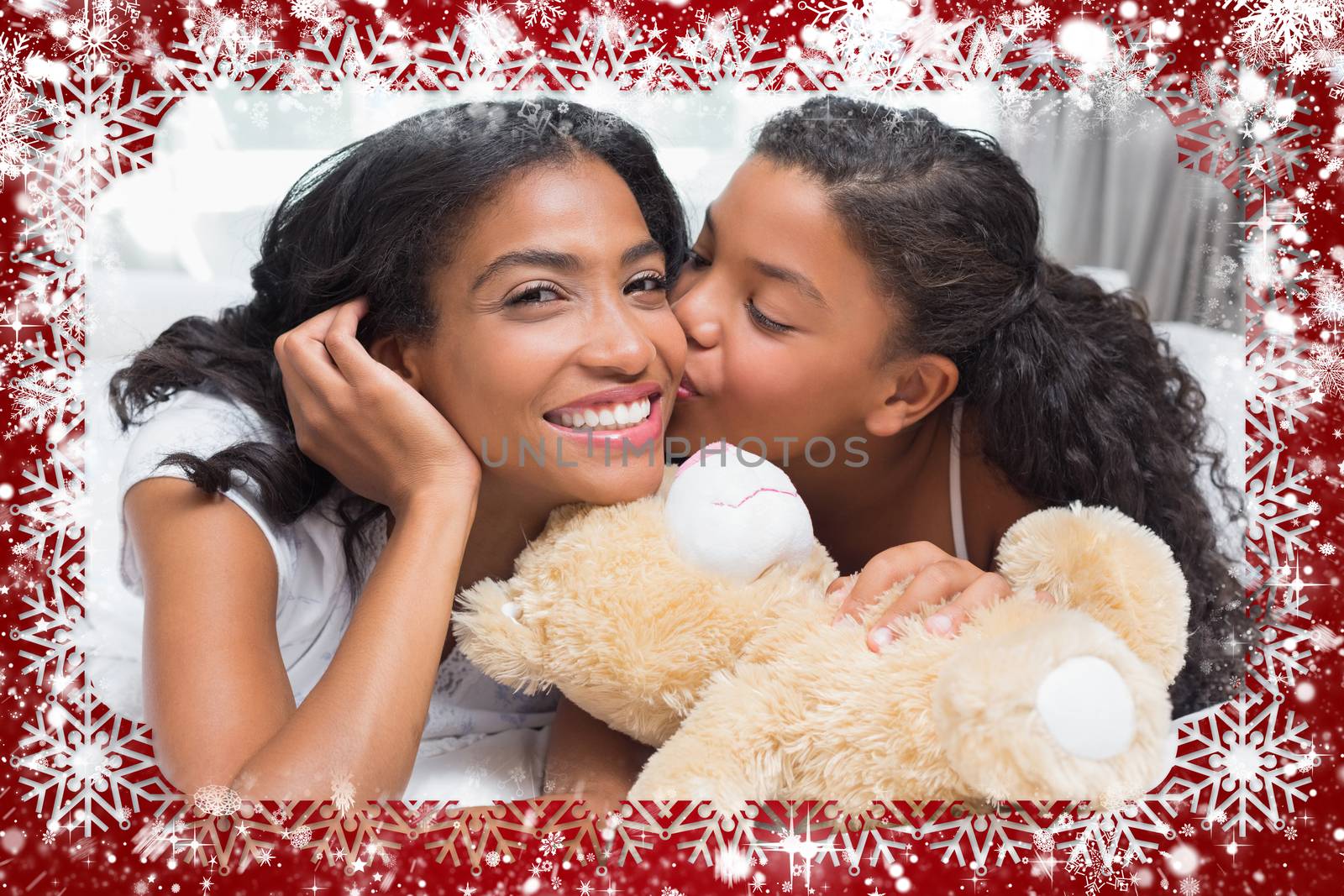 Pretty woman lying on bed with her daughter kissing cheek against snow