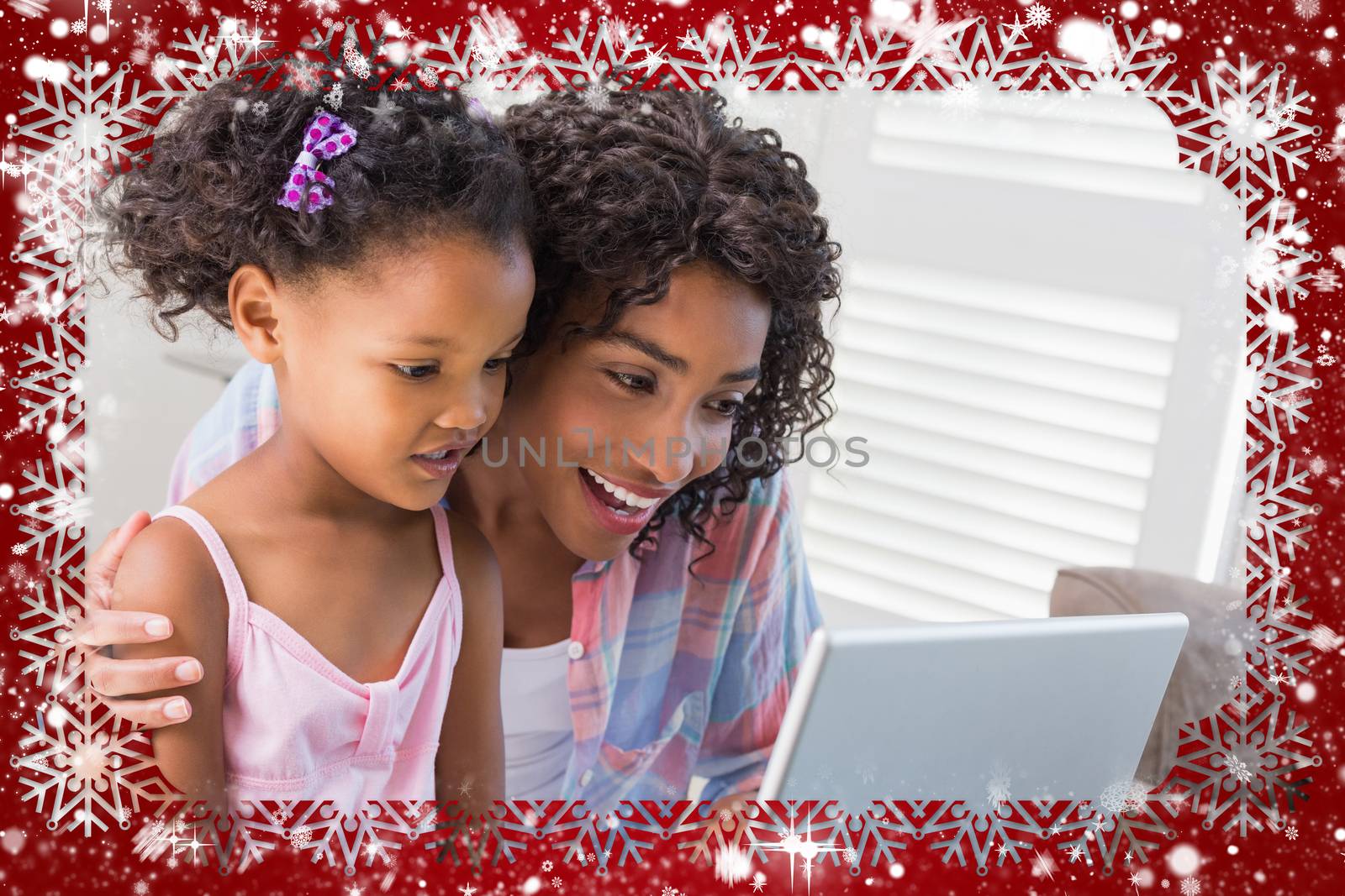 Cute daughter using laptop at desk with mother against snow