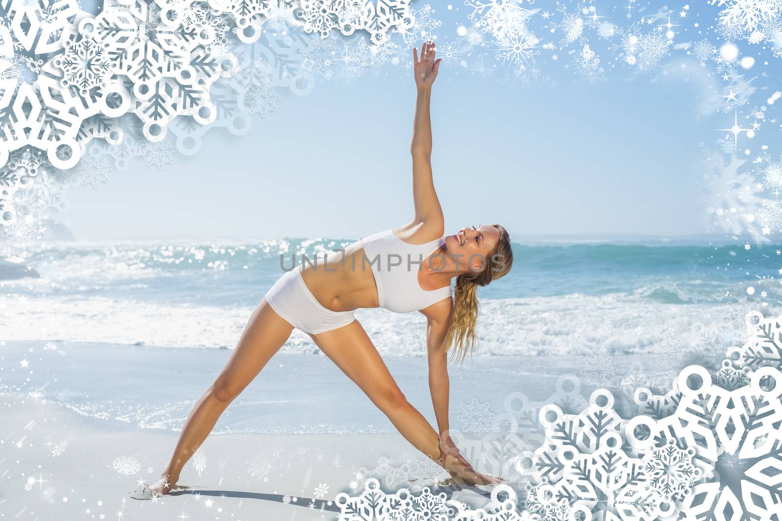 Gorgeous blonde standing in extended triangle pose by the sea against snow