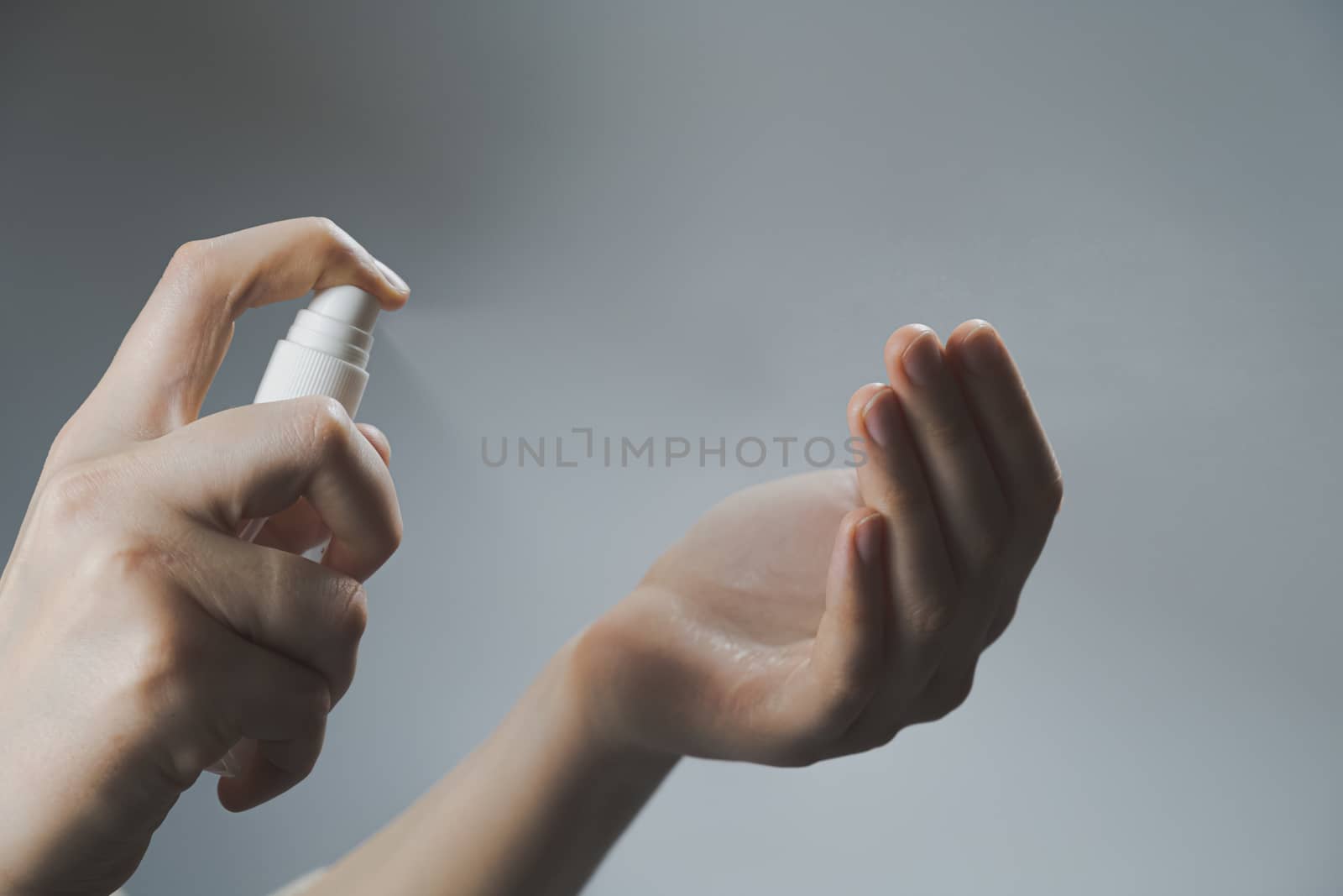 Cleaning hands with a personal sanitizer. Spraying hands, protec by photoboyko