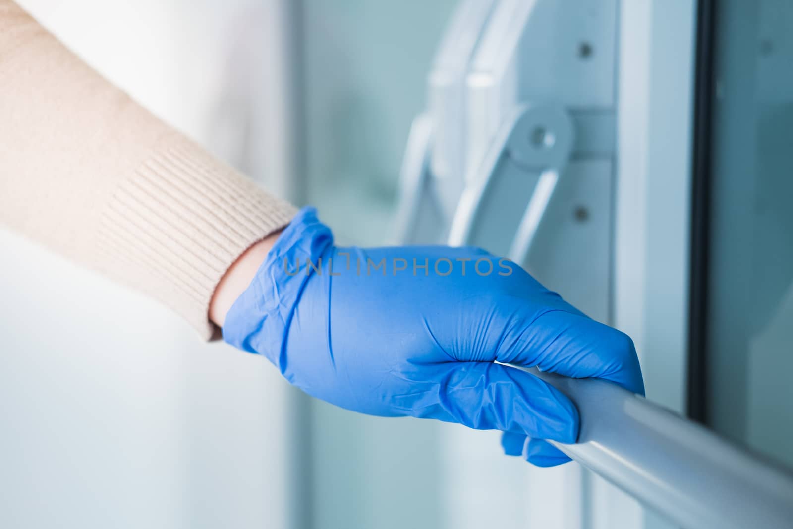 Hand in a rubber glove touches the handle of a door by photoboyko