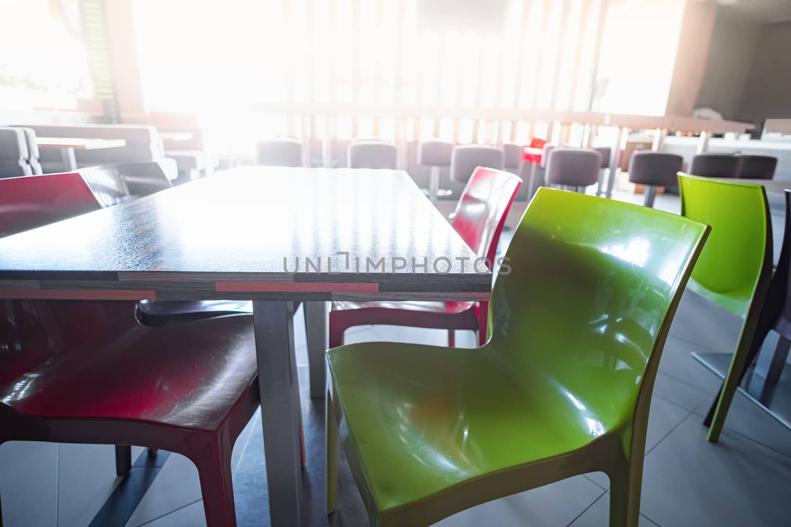 Empty food court at shopping centre or airport. Clean table and chairs against the bright light, generic interior, concept of lockdown due to quarantine