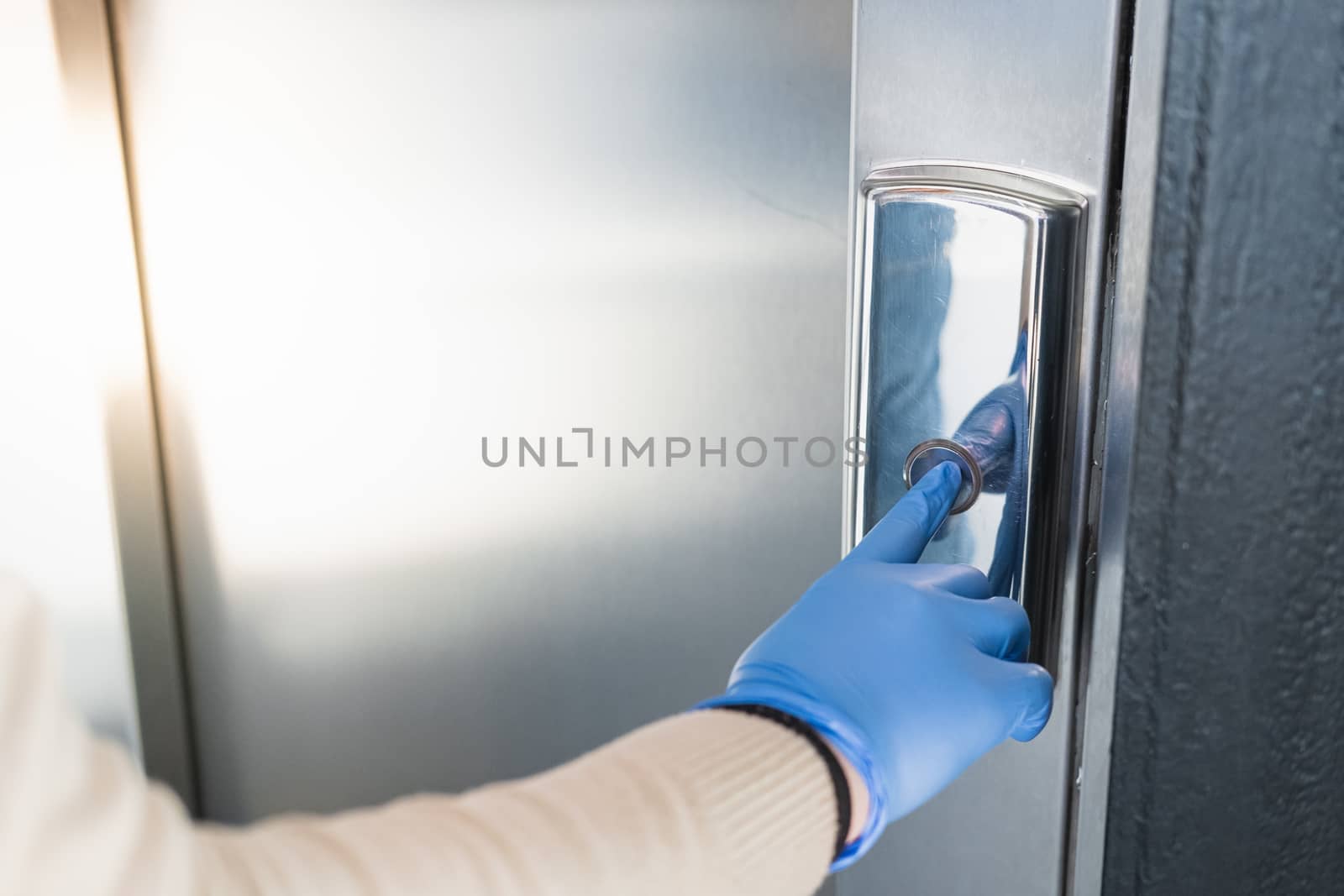 Hand in a rubber glove presses the elevator or lift button. Personal protection against germs, bacteria and virus: wearing hand gloves in public places