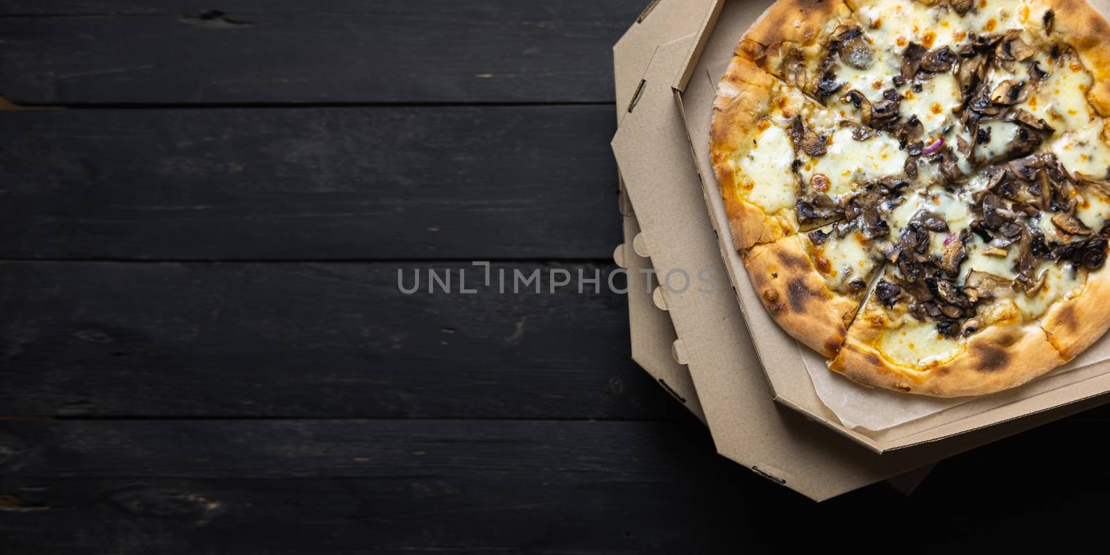 Pizza funghi in an open delivery box, dark backdrop by photoboyko