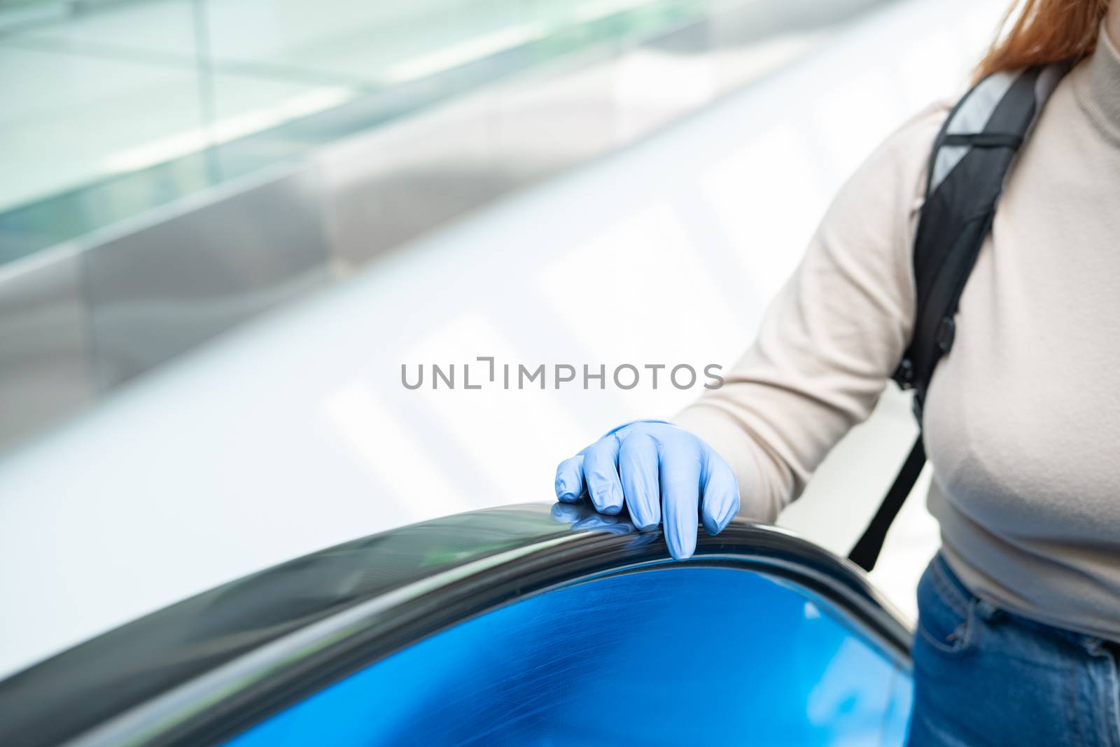 Hand in a rubber glove at escalator handlebar. by photoboyko