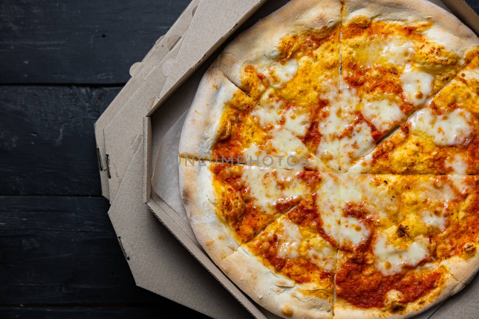 Pizza margherita in an open delivery box, low-key image. by photoboyko