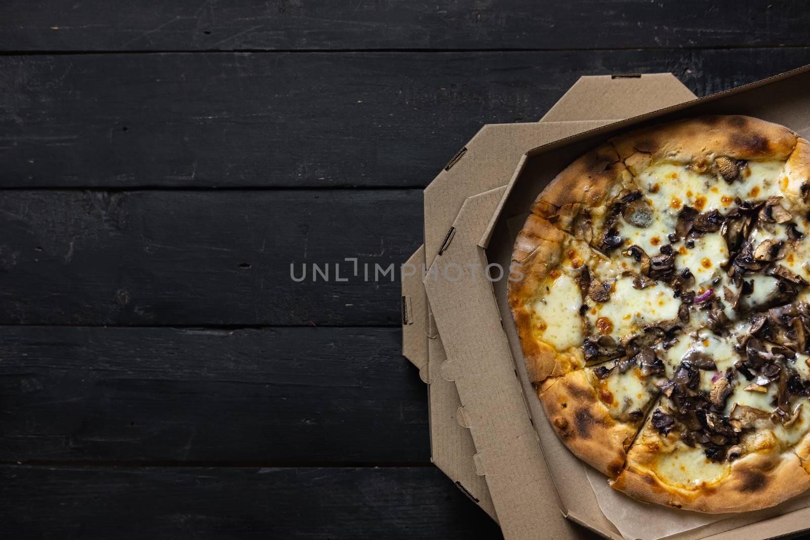 Pizza funghi in an open delivery box, dark backdrop. by photoboyko