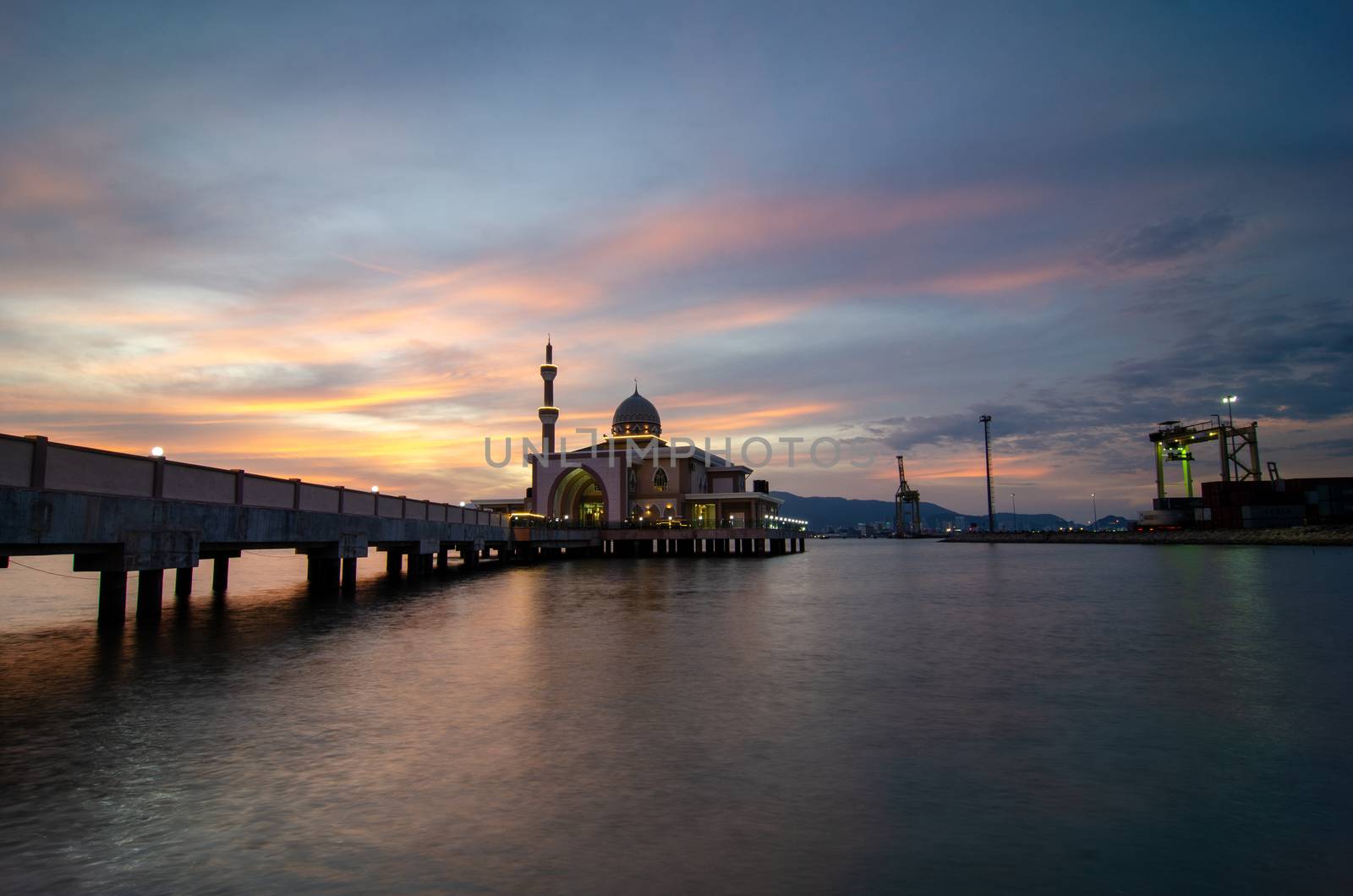 Butterworth, Malaysia floating mosque with dramatic sunset cloud with container terminal as background.