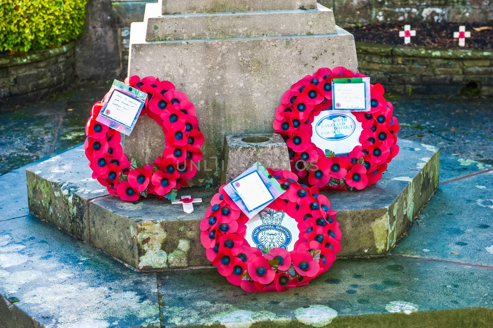 Poppy wreaths laid at the foot of the war memorial in remembrance of fallen soldiers and members of the armed forces UK