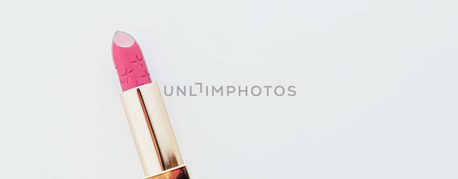 Luxury lipstick in a golden tube on white marble background, make-up and cosmetics concept