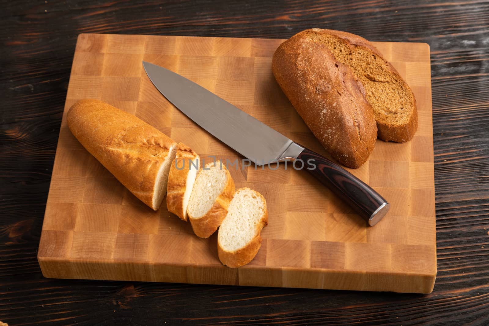 A loaf of bread sliced into slices with a knife on a wooden cutting board