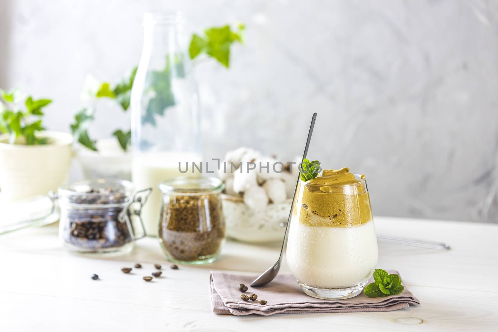 Glass with water drops of coffee trend - dalgona coffee, whipped instant coffee and ingredients on light rustic background, copy space.