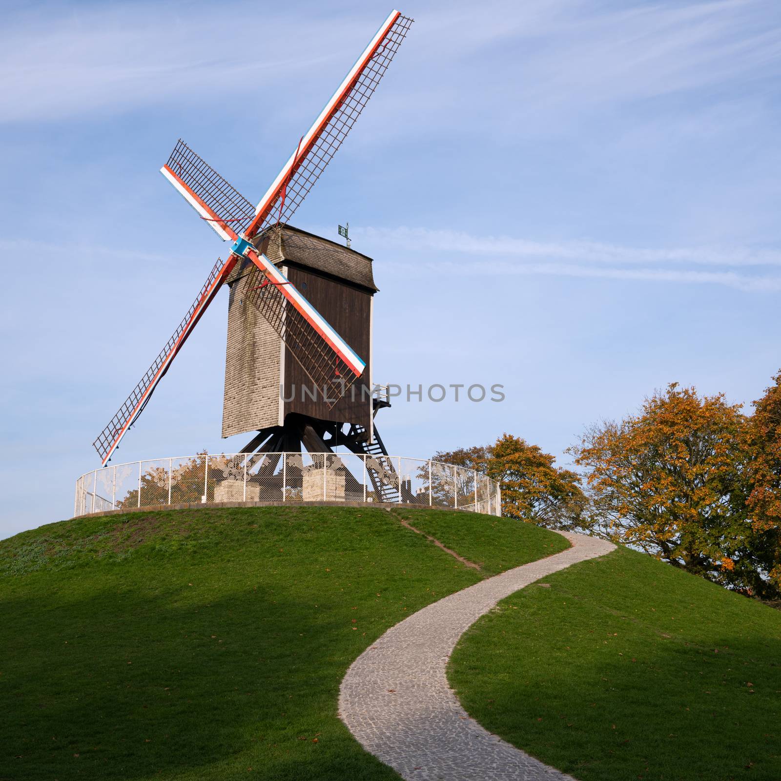 Historic windmill close to the canals of Bruges with autumnal colored trees, Belgium