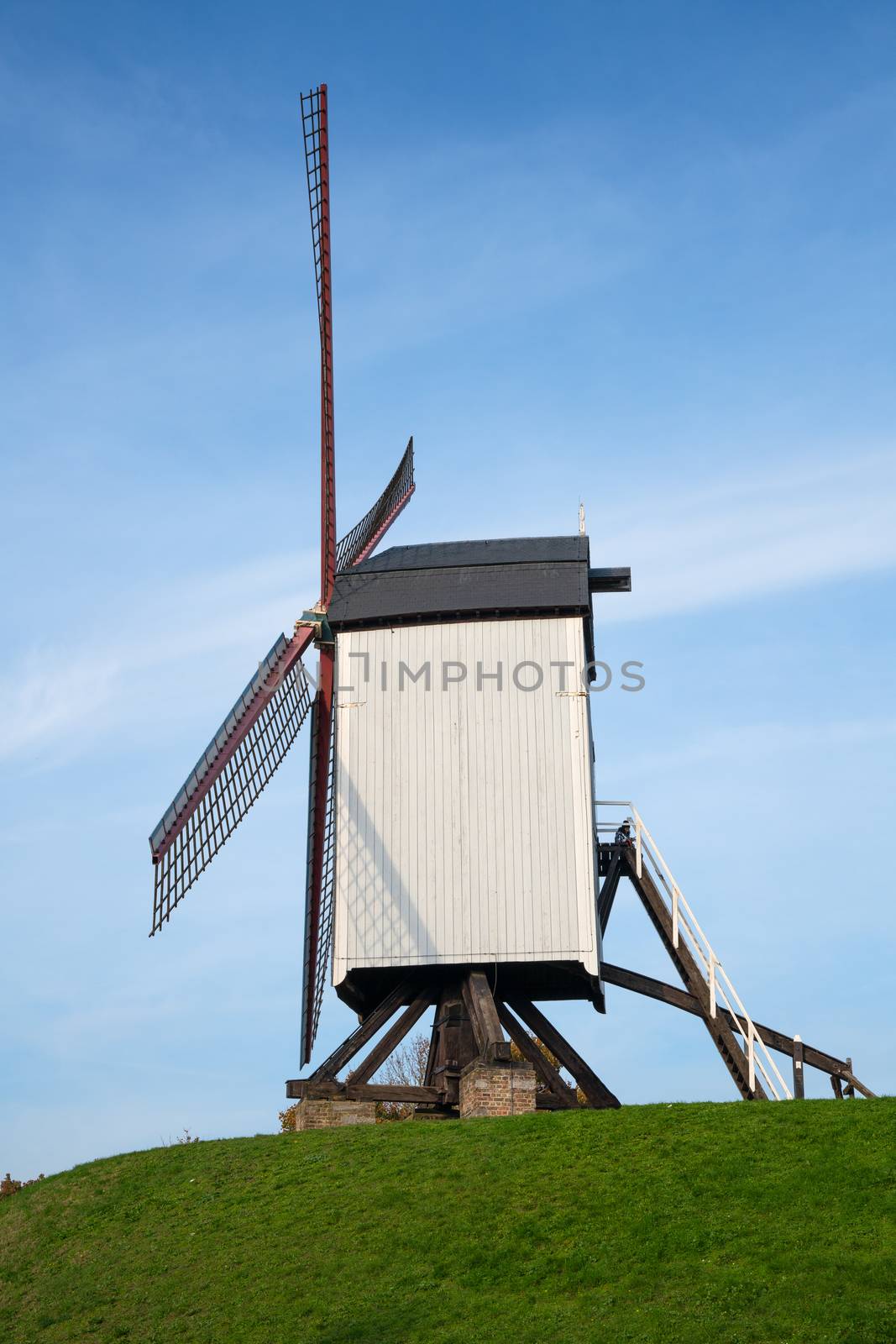 Historic windmill close to the canals of Bruges under clear blue sky, Belgium