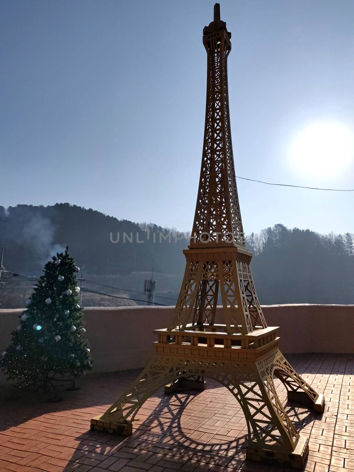 A second Eiffel Tower outside of Paris with Christmas decorations and sun in the background.