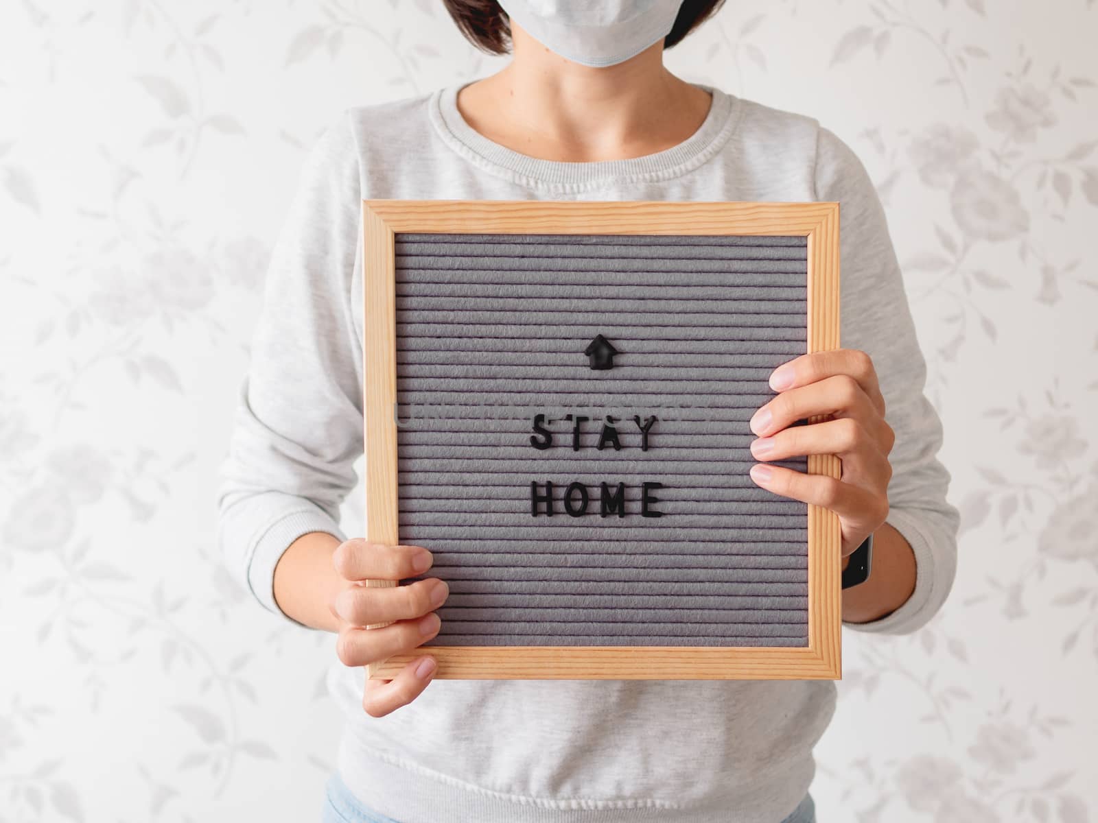 Woman in medical mask with letter board. Phrase STAY HOME. Quarantine because of coronavirus COVID19. Self-isolation at home.