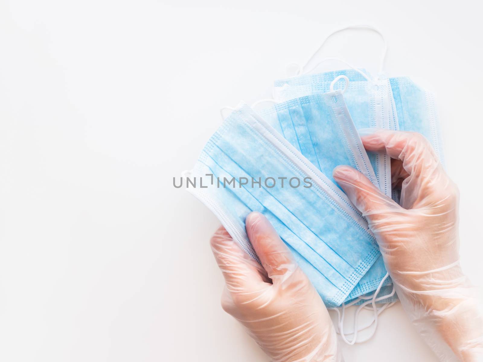 Top view on doctor's hands with pack of blue protective medical masks. Coronavirus COVID-19 concept on white background with copy space.