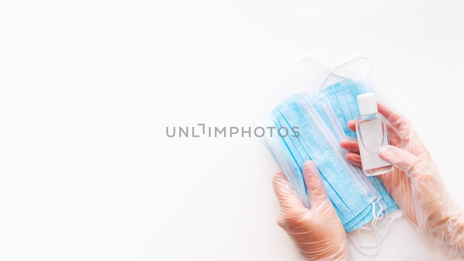 Top view on doctor's hands in protective gloves with medical masks and sanitizer in transparent bottle. Coronavirus COVID-19 concept on white background with copy space.