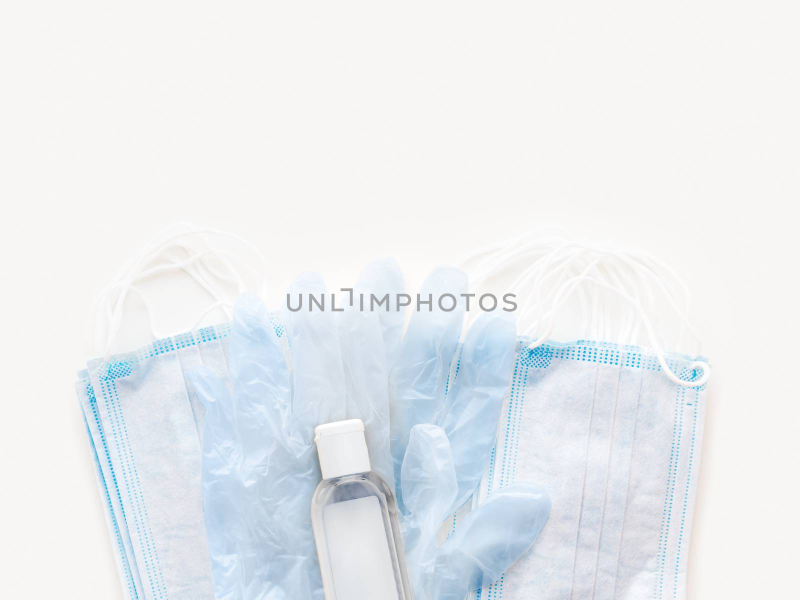 Top view on pack of blue medical masks, protective rubber gloves and transparent bottle with sanitizer gel. Coronavirus COVID-19 concept on white background.