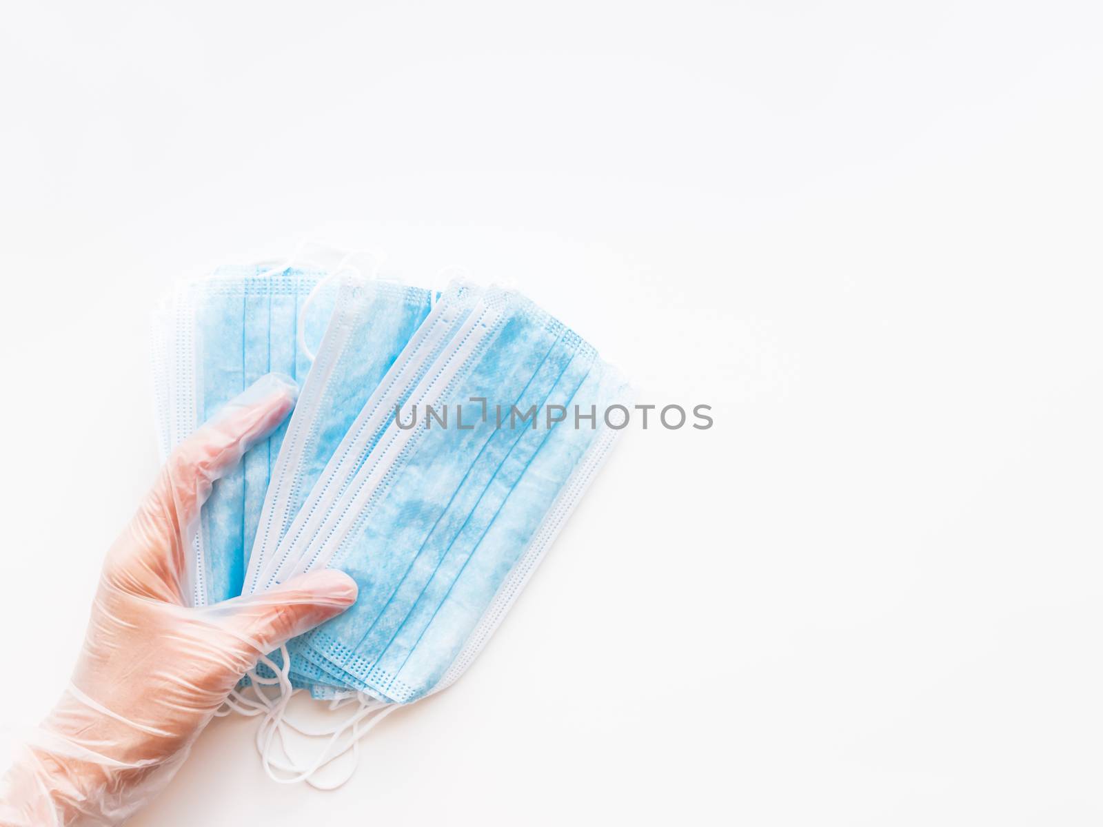 Top view on doctor's hand with pack of blue protective medical masks. Coronavirus COVID-19 concept on white background with copy space.