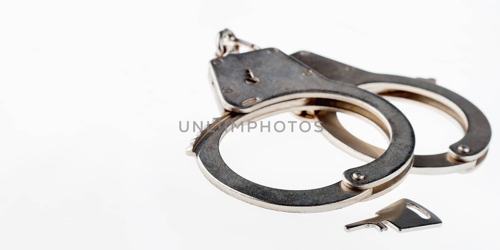 Locked handcuffs on wooden background. Legal responsibility for violating or crime. Banner with white copy space.