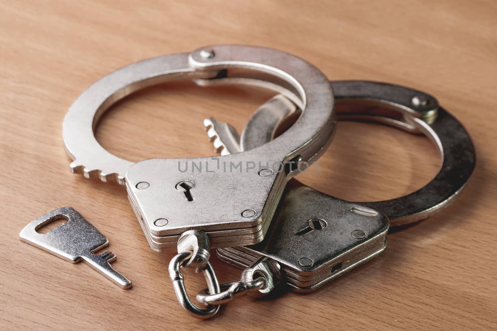 Locked handcuffs on wooden background. Legal responsibility for violating or crime.