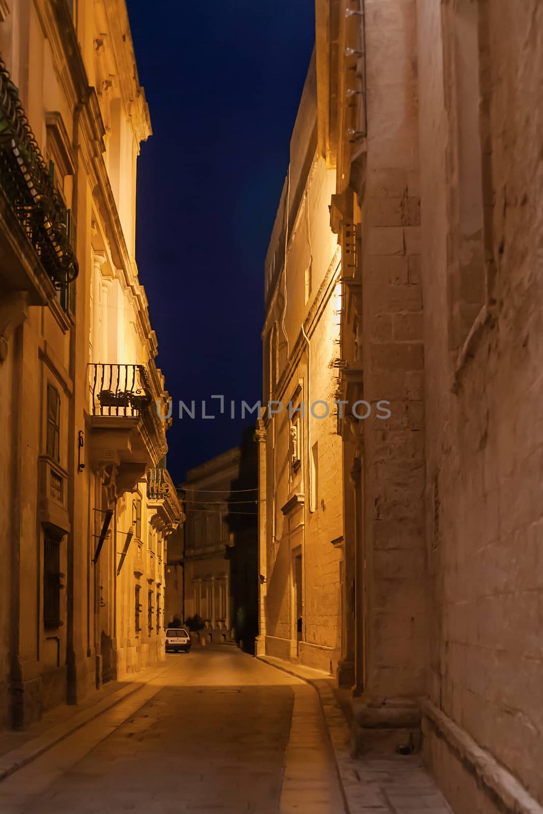 Illuminated narrow streets of Mdina, ancient capital of Malta. Night view on buildings and wall decorations of ancient town.