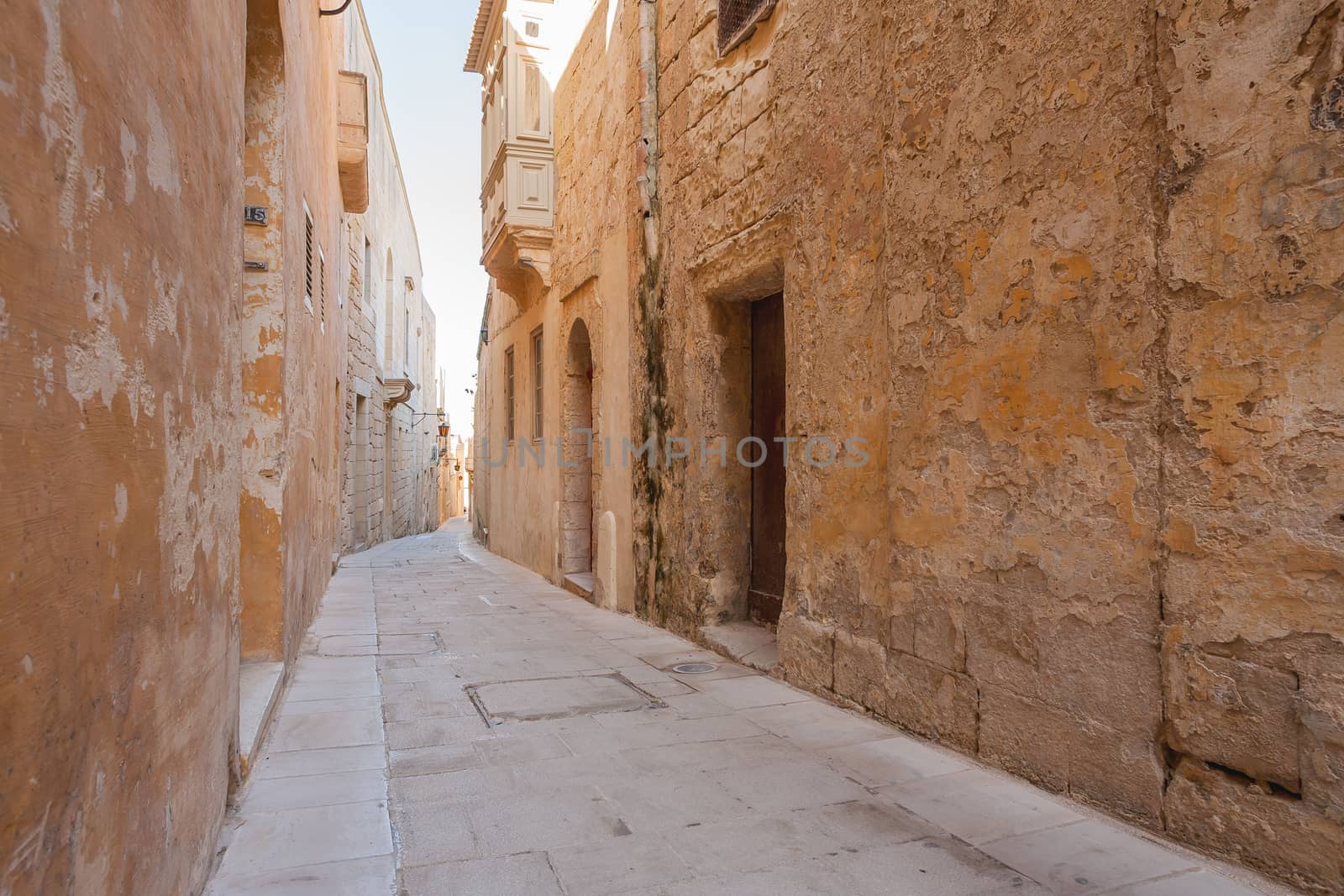 Narrow streets of Mdina, old capital of Malta. Stone buildings with old fashioned doors and balconies. by aksenovko