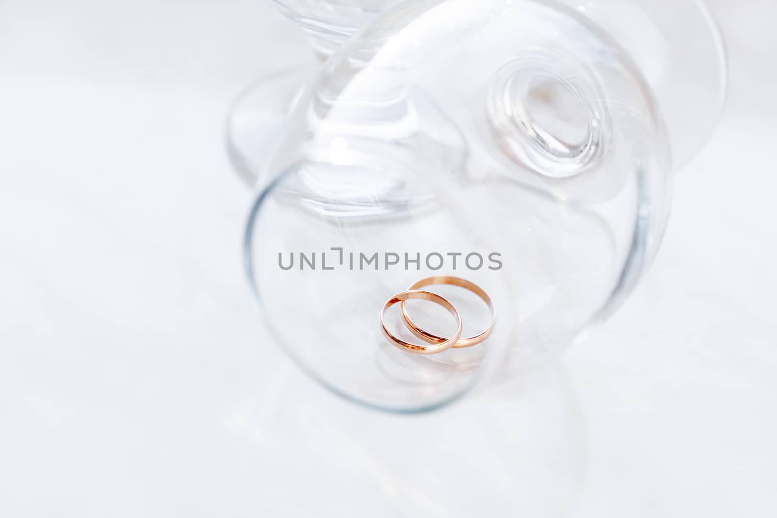 Golden wedding rings inside transparent wine glass. Symbol of love and marriage.