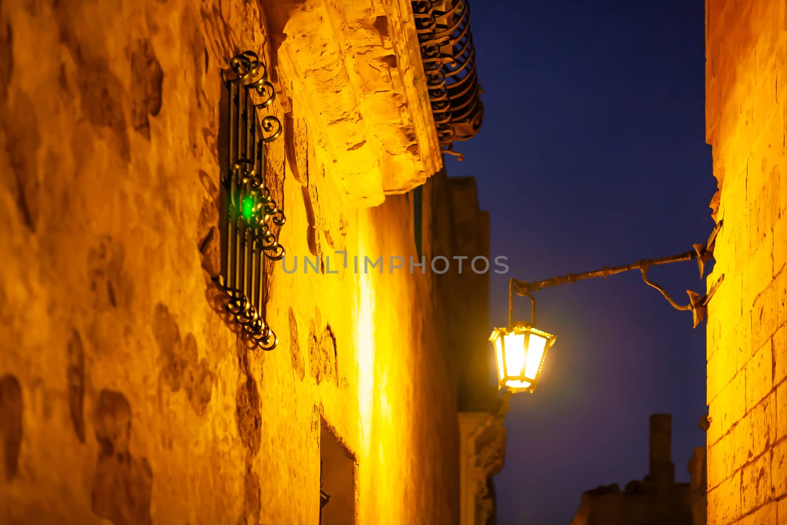 Narrow streets of Mdina, ancient capital of Malta. Night view on illuminated buildings and wall decorations of ancient town.