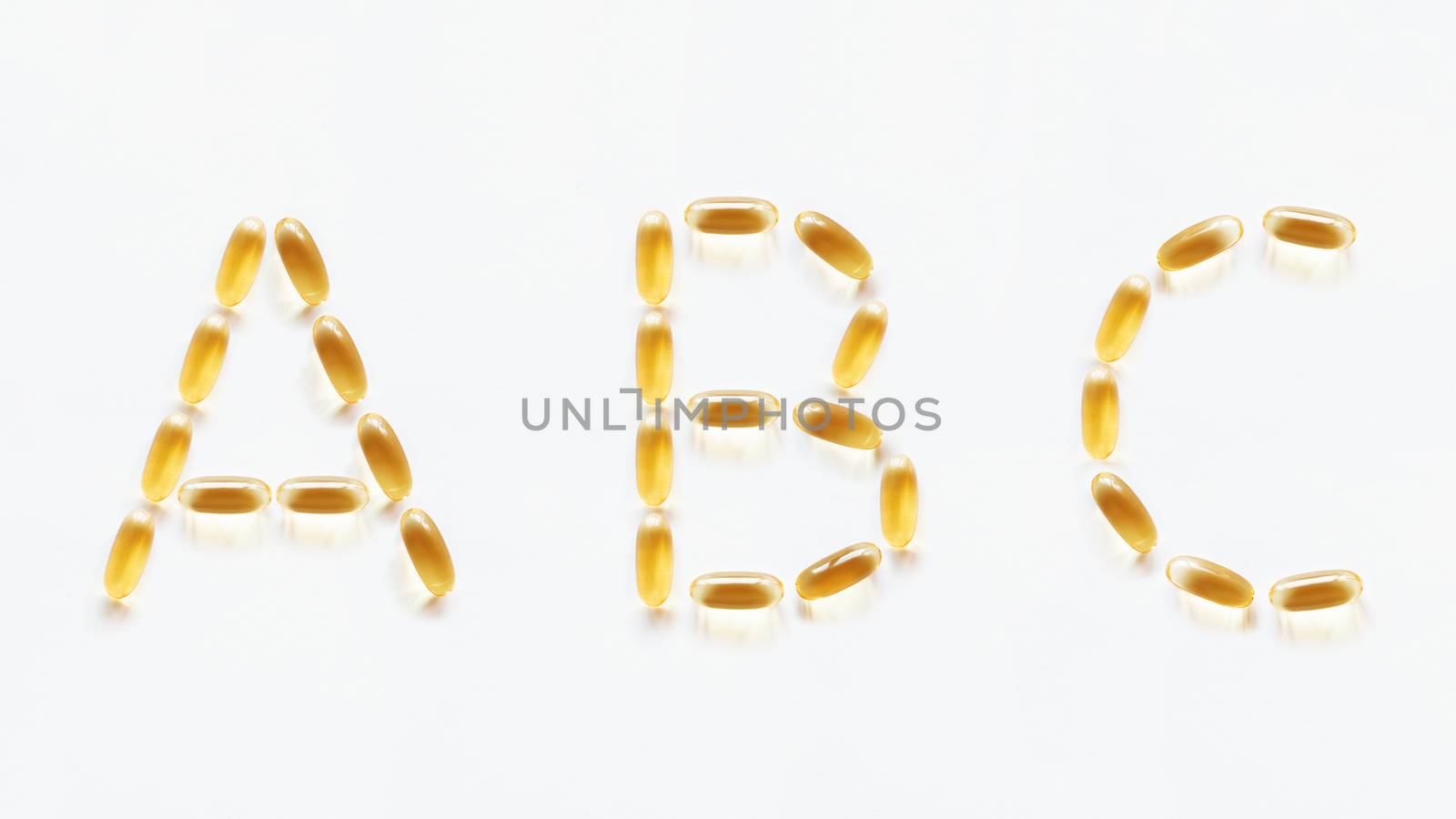 Letters A, B, C made of transparent yellow pills. Part 1 of latin alphabet in medical style. Isolated on white background.