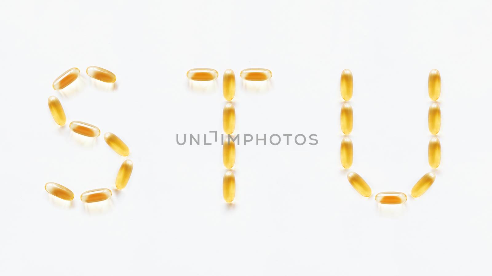 Letters S, T, U made of transparent yellow pills. Part 7 of latin alphabet in medical style. Isolated on white background.