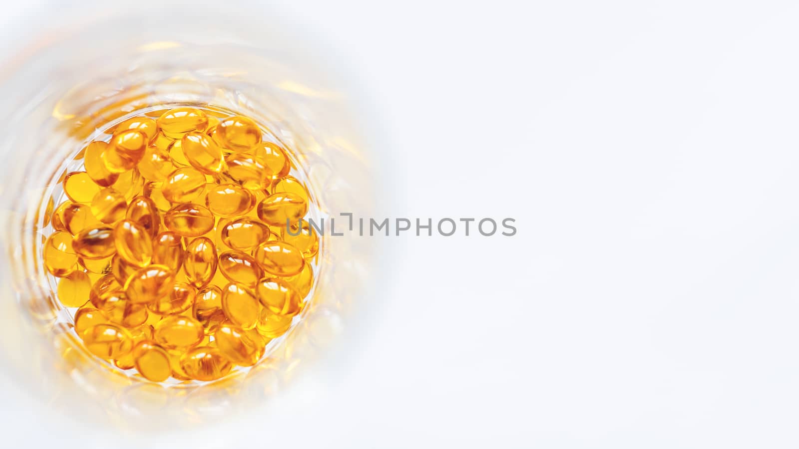 Orange pills inside glass jar. Top view on medicine capsules. White background with copy space. by aksenovko