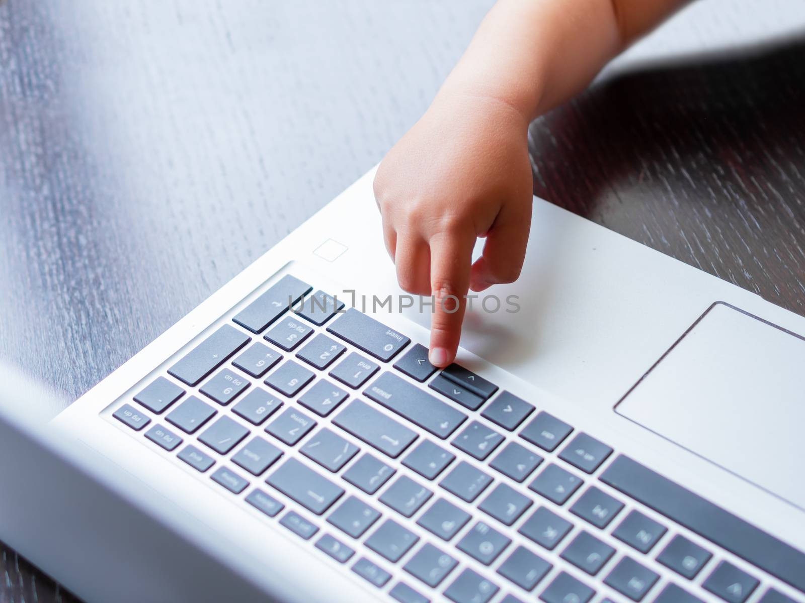 Child explores silver metal laptop. Curious toddler boy presses buttons. by aksenovko