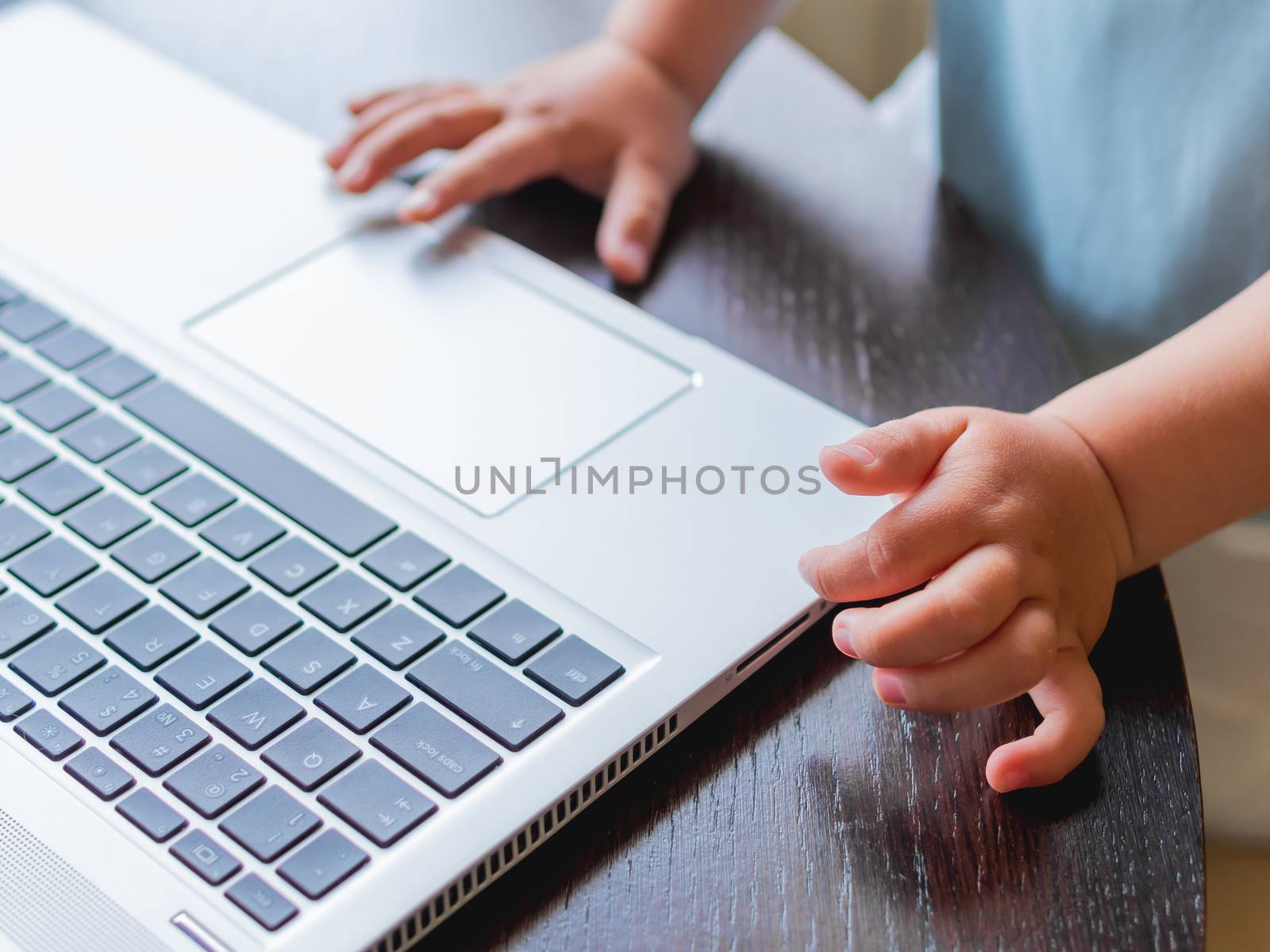 Child studies the laptop. Toddler boy's hands on device 's touchpad. by aksenovko