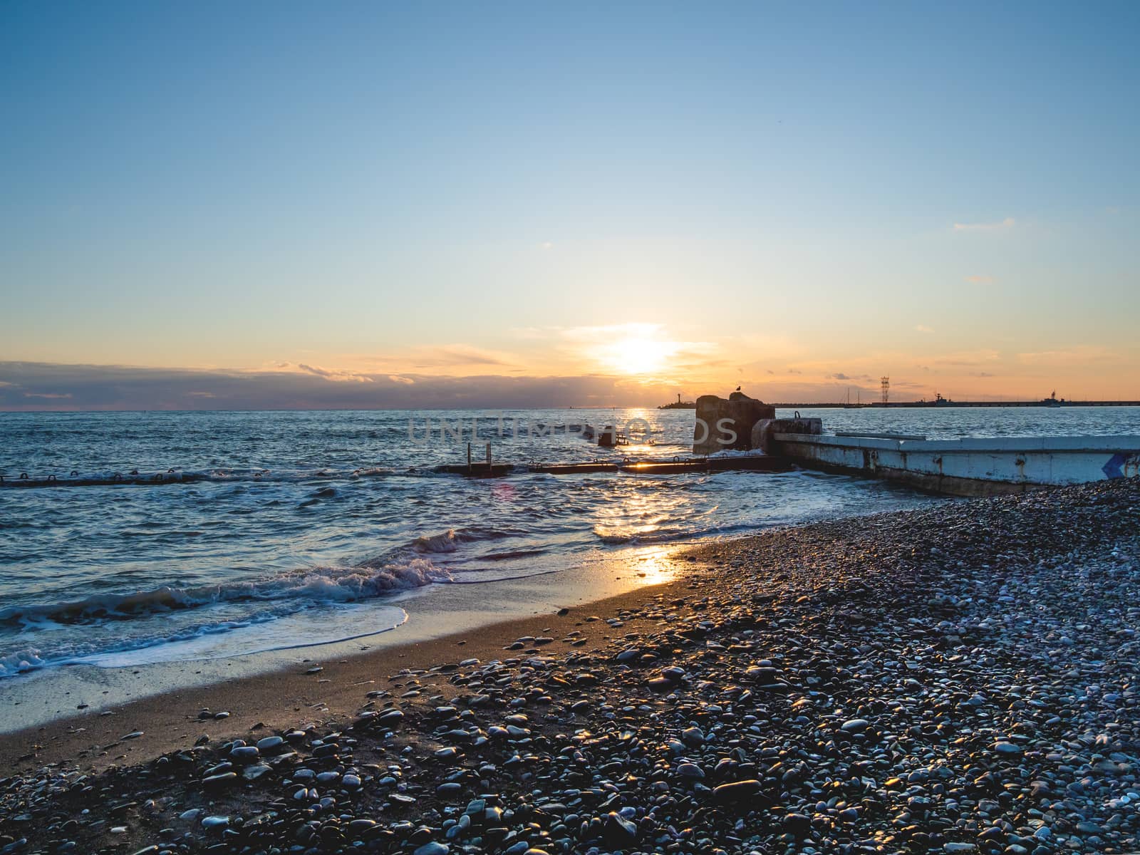 Beautiful sunset over Black sea in Sochi, Russia. Silhouettes of seagulls on rocks and tranquil sea surf.