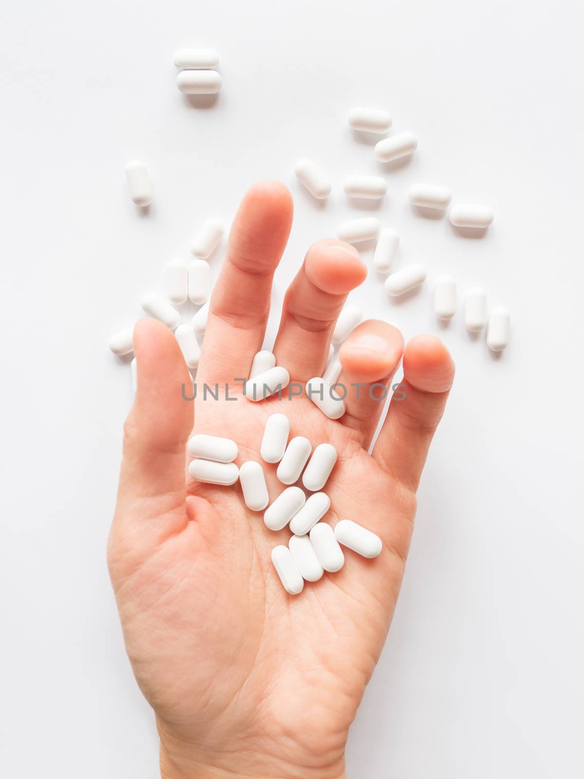 Palm hand full of white scattering pills. Capsules with medicines on light background. Flat lay, top view. by aksenovko