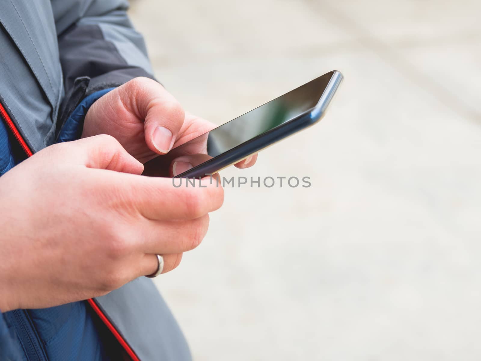 Man's hands with smartphone. Man is texting to somebody. Background with copy space.