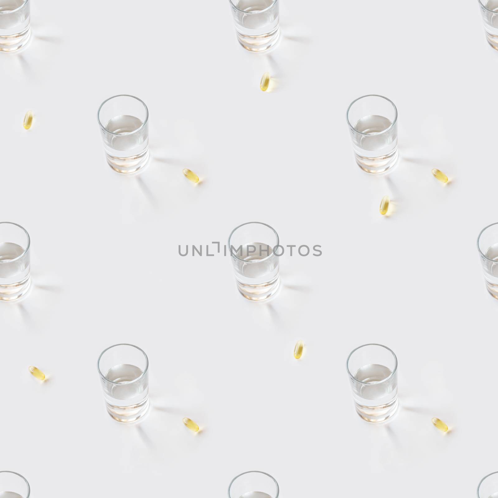 Seamless photo pattern with glass of pure water and yellow pills. Sun shines through transparent liquid on white background and scattered drugs.