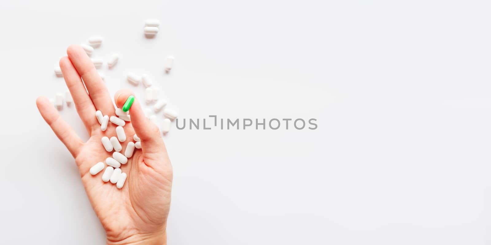 Palm hand full of white and green one scattering pills. Capsules with medicines on light background. Flat lay, top view. by aksenovko